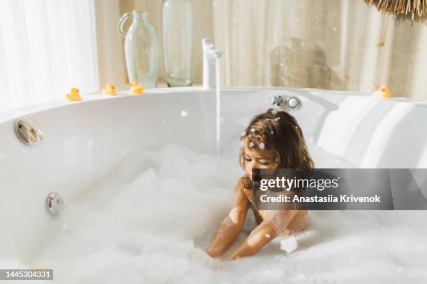 little girl having fun in bath with foam at home. - bubble bath stock pictures, royalty-free photos & images
