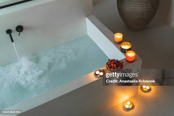 burning scented candles near bathtub. - schaumbad stock-fotos und bilder