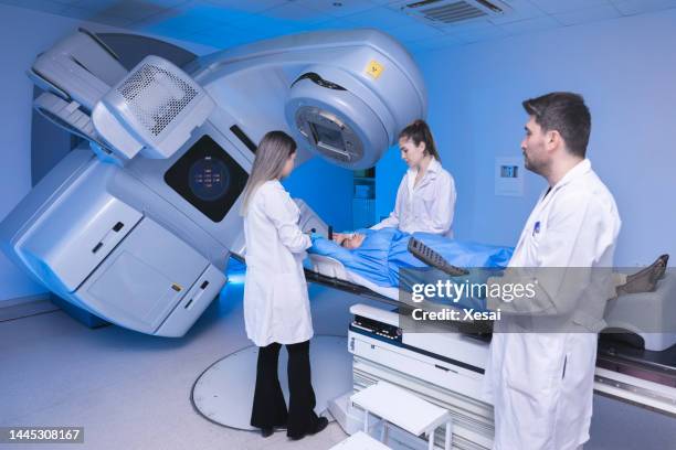 cancer treatment in a modern medical private clinic or hospital with a linear accelerator. professional doctors team working while the woman is undergoing radiation therapy for cancer - straling stockfoto's en -beelden