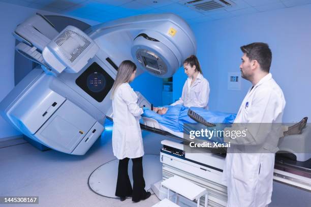cancer treatment in a modern medical private clinic or hospital with a linear accelerator. professional doctors team working while the woman is undergoing radiation therapy for cancer - radiotherapy stock pictures, royalty-free photos & images
