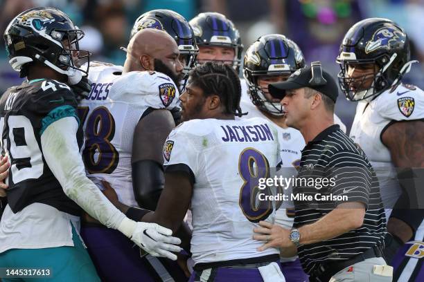 Lamar Jackson of the Baltimore Ravens and coach John Harbaugh try to keep Morgan Moses of the Baltimore Ravens away from the Jacksonville Jaguars at...