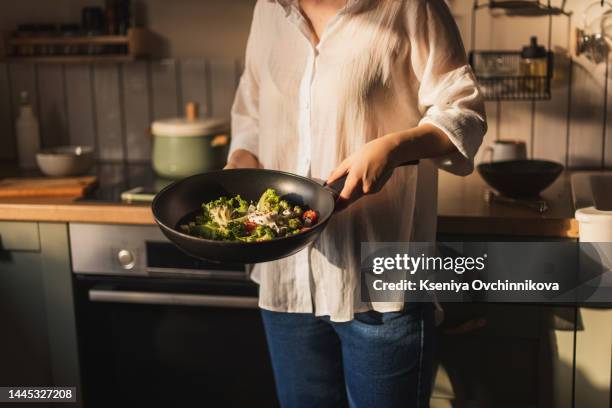 caucasian senior woman hand with fork stirring frying vegetables in frying pan, close-up - stir frying european stock pictures, royalty-free photos & images