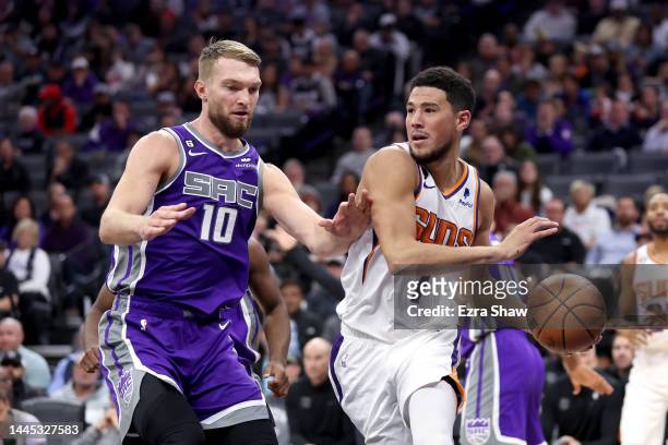 Devin Booker of the Phoenix Suns is guarded by Domantas Sabonis of the Sacramento Kings at Golden 1 Center on November 28, 2022 in Sacramento,...