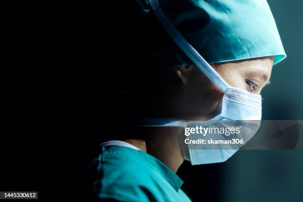 facial expression close-up of a young adult female surgeon operating and wearing a surgical mask and copy space - chirurgenkappe stock-fotos und bilder