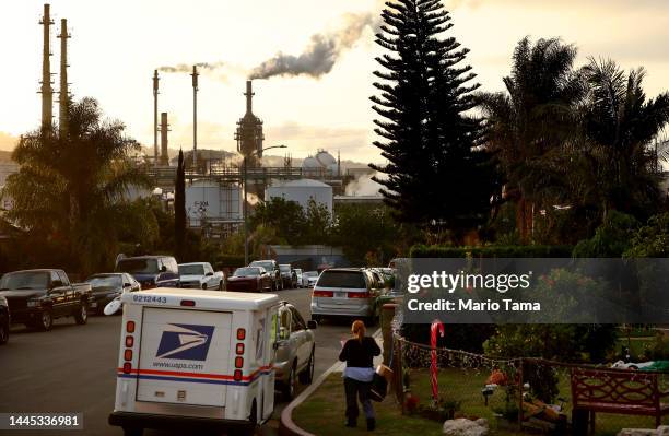 Mail carrier works on a residential street near the Phillips 66 Los Angeles Refinery Wilmington Plant on November 28, 2022 in Wilmington, California....