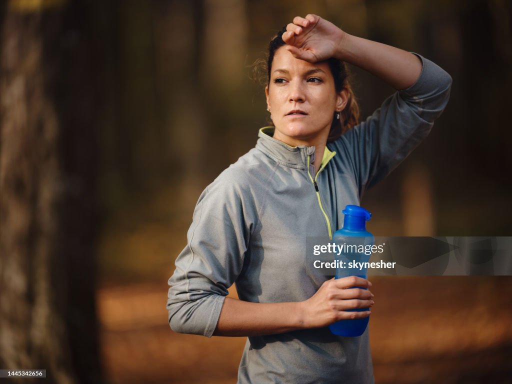 Sweaty Female Athlete Having A Water Break In Autumn Day At The Park
