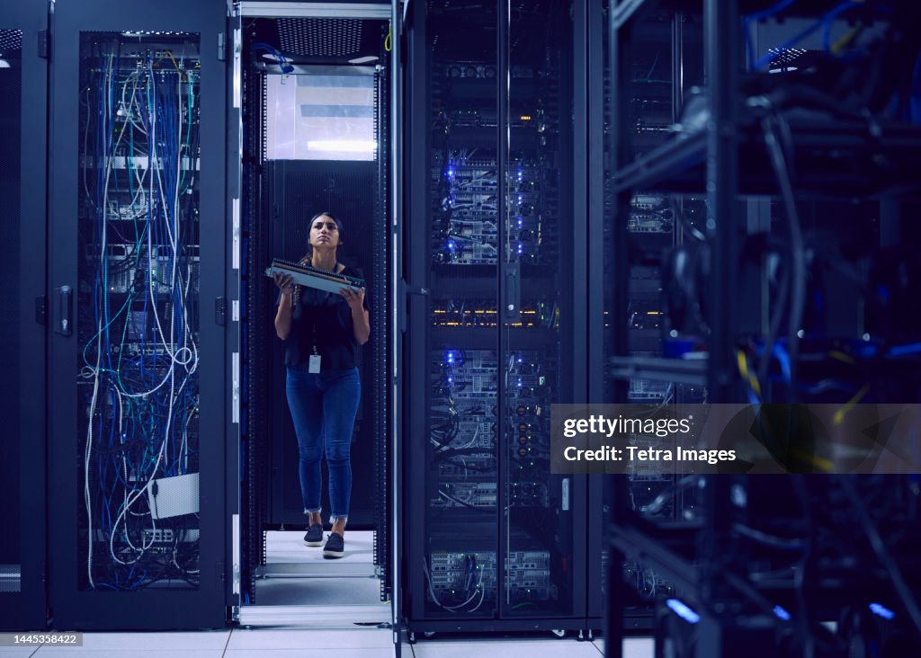 Female technician carrying hard drive in server room