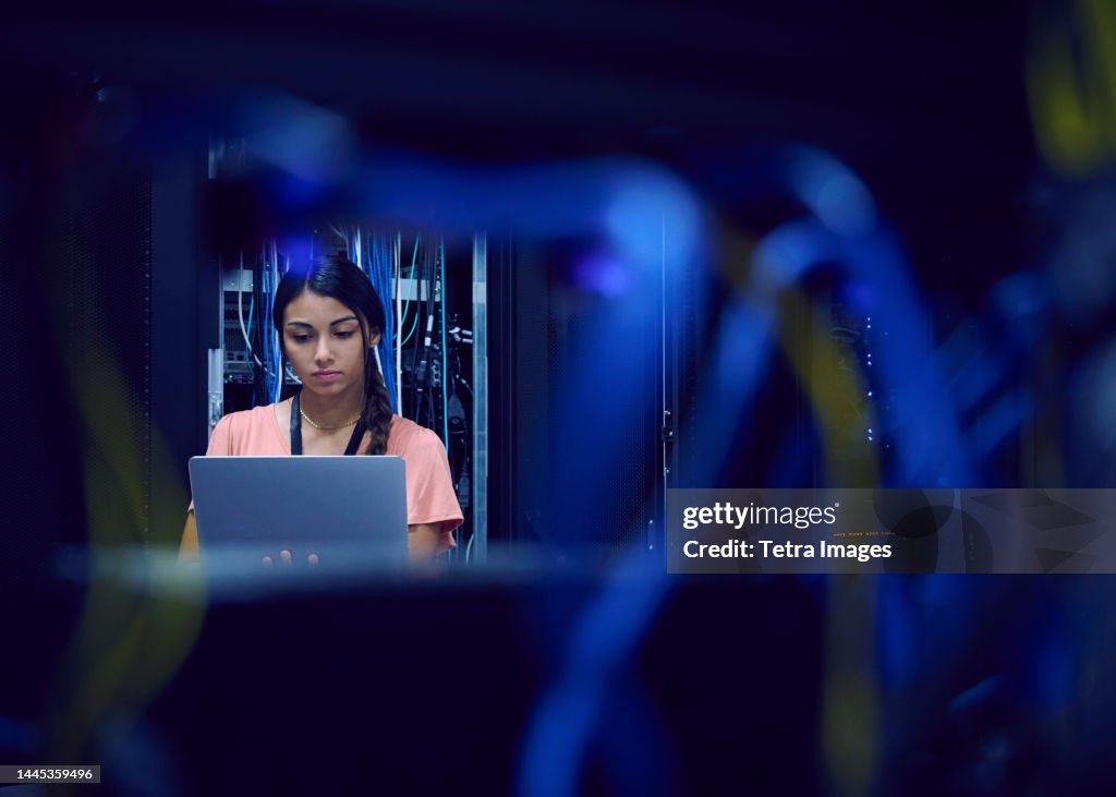 Female technician using laptop in server room