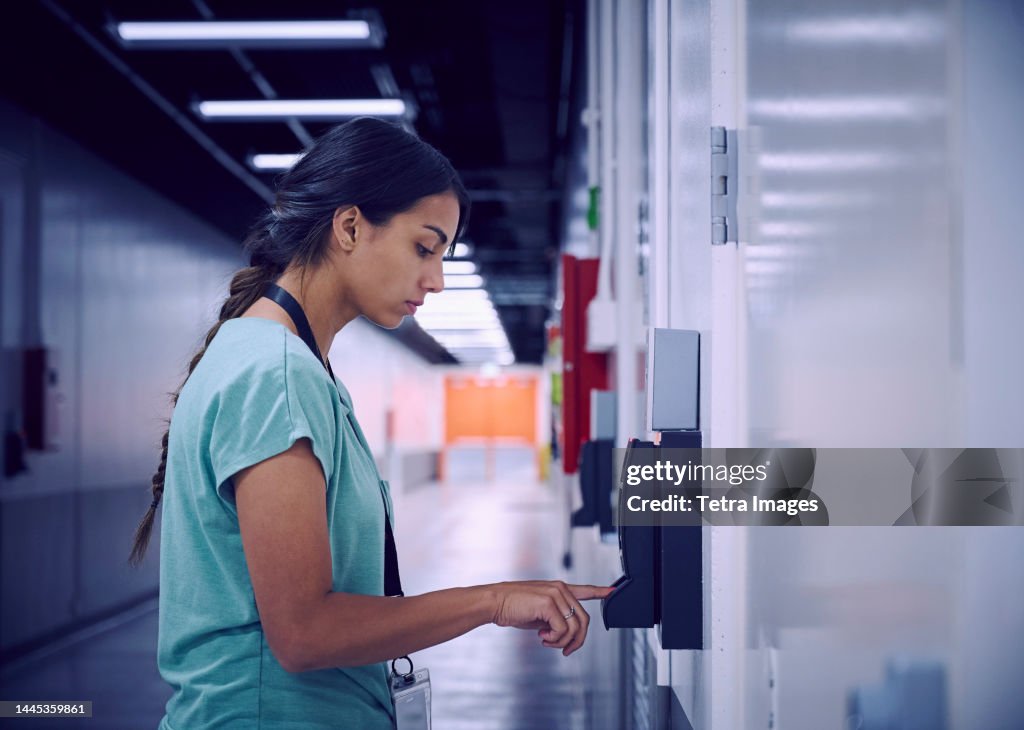 Woman using digital fingerprint scanner in office