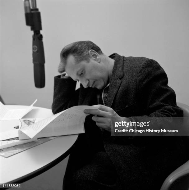 Author Studs Terkel sitting at table, looking through papers, microphone visible at upper left in circa 1950.