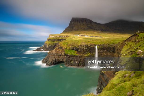 mulafossur waterfall and the little village of gasadalur, vagar island, faroe islands, denmark, europe - faroe islands stock-fotos und bilder