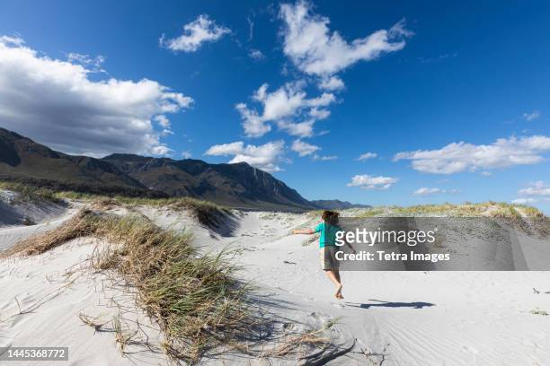 south africa, hermanus, boy (8-9) running on sandy on grotto beach - hermanus stock pictures, royalty-free photos & images