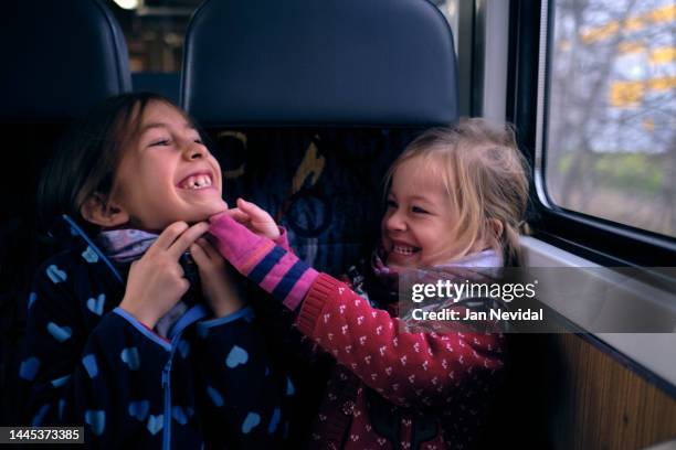 two sisters happily playing together in the train - teasing stock pictures, royalty-free photos & images