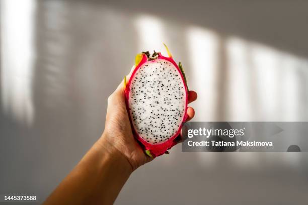 cut dragon fruit in hand on a white background on a sunny day. - pitaya stock pictures, royalty-free photos & images