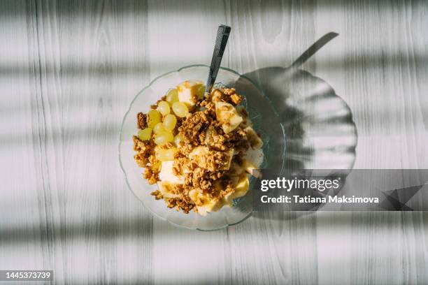 granola with yogurt and fruits in a glass plate, top view. - corn flakes stock pictures, royalty-free photos & images