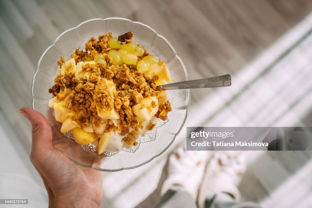 Granola with yogurt and fruits in a glass plate, top view.