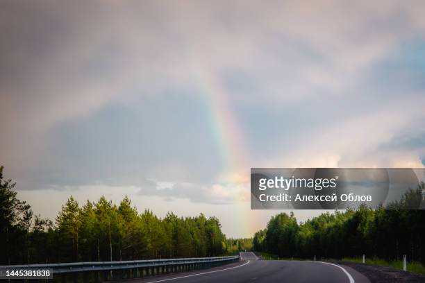 asphalt road under the clouds. top view of the road through the green summer forest. rainbow over the forest in karelia - rainbow forrest abstract bildbanksfoton och bilder
