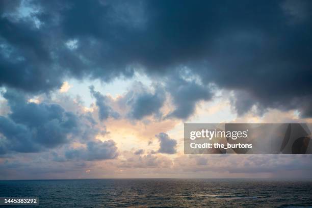 dramatic sky and dark clouds during sunset by the sea - cielo minaccioso foto e immagini stock