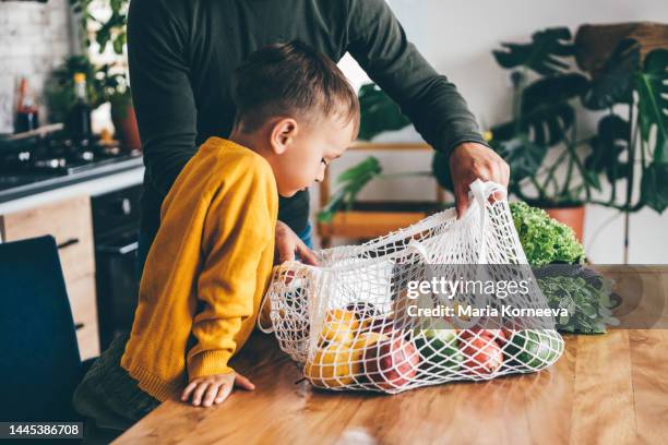 parents and children unpacking grocery in kitchen. - familienessen stock-fotos und bilder