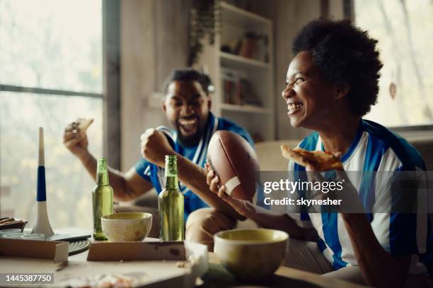 cheerful black couple cheering while watching a ruby match at home. - rugby fan stock pictures, royalty-free photos & images