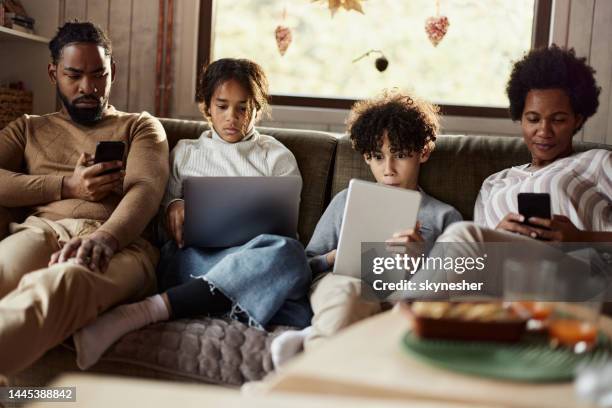 relaxed black family using wireless technology at home. - mother and son using tablet and laptop stock pictures, royalty-free photos & images