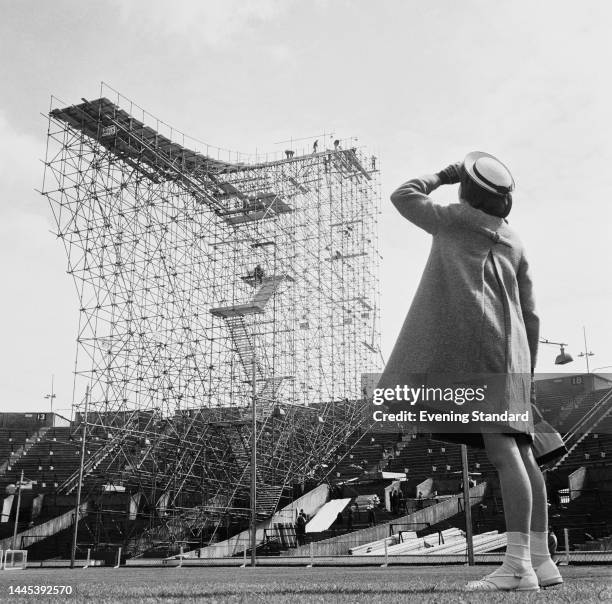 Woman looking up at the ski jumping ramp under construction inside Wembley Stadium in London for the International Ski Jumping Contest on May 30th,...