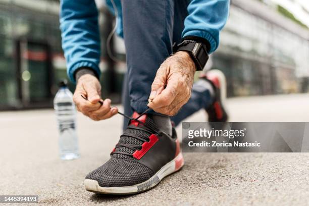 il corridore senior allaccia il laccio delle scarpe - calzature sportive foto e immagini stock