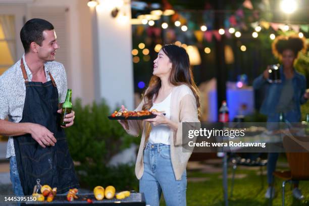 young couple enjoy talking in the garden barbecue party - couple grilling stock pictures, royalty-free photos & images