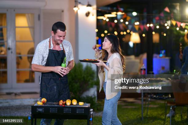 young couple enjoy talking in the garden barbecue party - couple grilling stock pictures, royalty-free photos & images