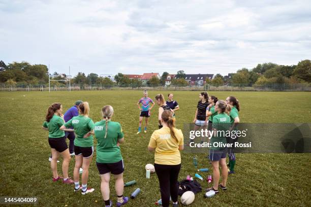 women's rugby team standing on sports field listening to coach - rugby pitch stock pictures, royalty-free photos & images