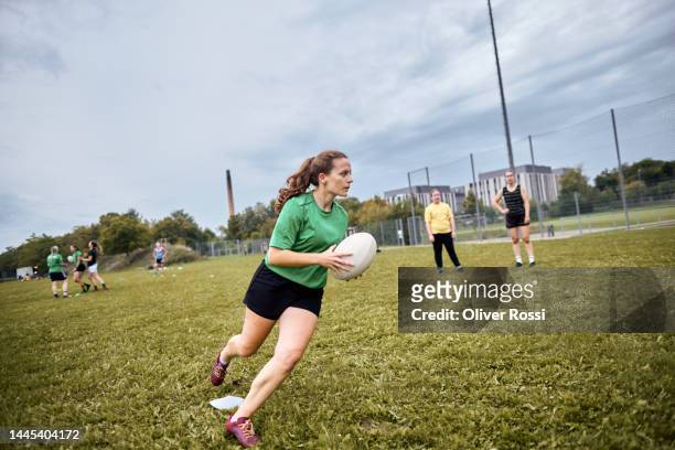 female rugby player running with ball on sports field - rugby - fotografias e filmes do acervo