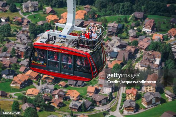 the cable car to the männlichen mountain peak in the lauterbrunnen valley, switzerland. in the background the village of wengen - wengen stock pictures, royalty-free photos & images