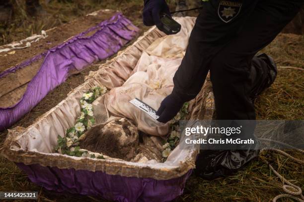 Police officer takes. Photograph and measurements of the body of a 16-year-old girl that was exhumed by local residents, police, forensic experts and...