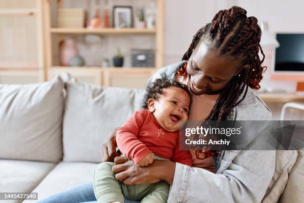 kleiner lächelnder kleiner junge und seine mutter - black mother holding newborn stock-fotos und bilder