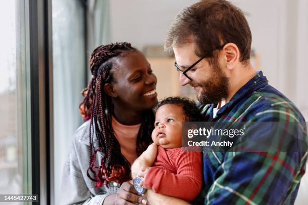 bella famiglia che gode della giornata a casa con il neonato - multi ethnic foto e immagini stock