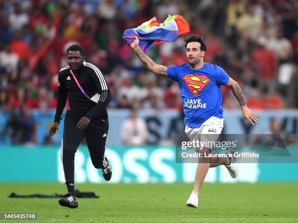 Pitch invader wearing a shirt reading "Save Ukraine" holds a rainbow flag during the FIFA World Cup Qatar 2022 Group H match between Portugal and...