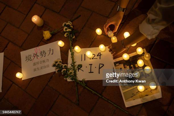 Protester places a candle on the ground during a vigil commemorating victims of China's Covid Zero policy at the University of Hong Kong on November...
