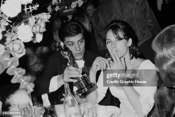 French actor Alain Delon and his wife, French actress and fashion model Nathalie Delon attend the 37th Academy Awards, held at the Santa Monica Civic...