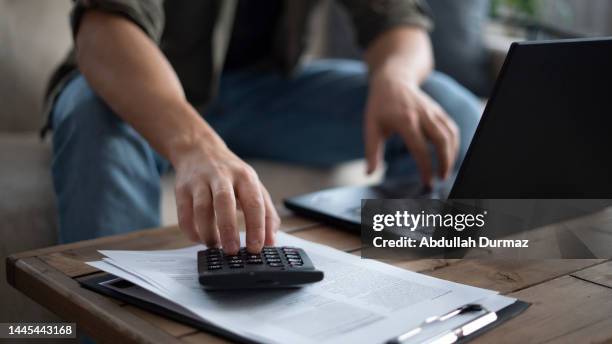 close-up young man pays house bills from laptop - accounting calculator stock pictures, royalty-free photos & images