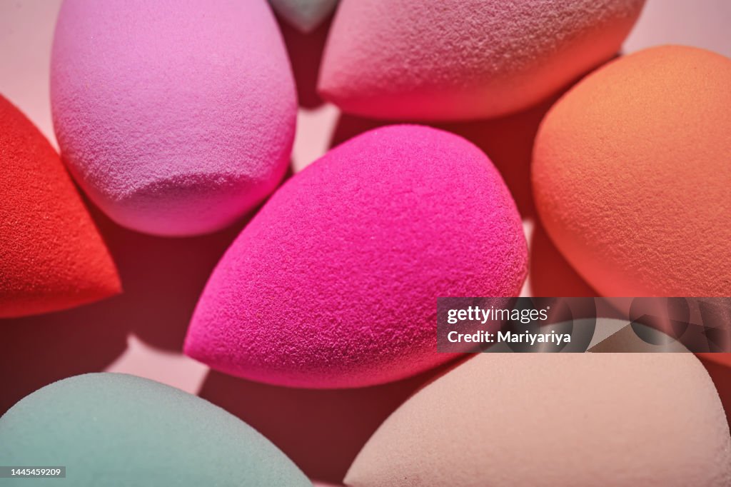 A set of makeup sponges on a pink background close-up.