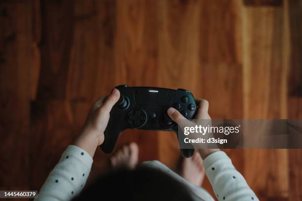 overhead view of a little asian girl holding a game controller, playing video games and having fun at home. kids entertainment - losing virginity - fotografias e filmes do acervo