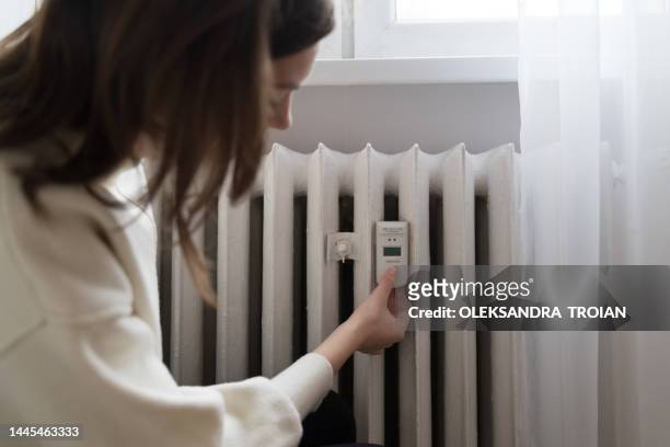 young woman near the home radiator with temperature sensor - water heater stockfoto's en -beelden