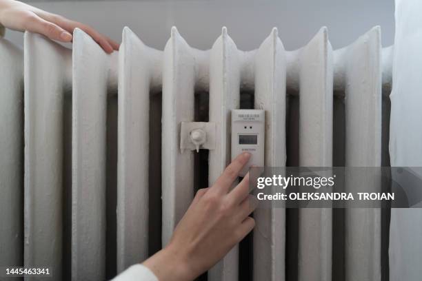 young woman near the home radiator with temperature sensor - radiador fotografías e imágenes de stock
