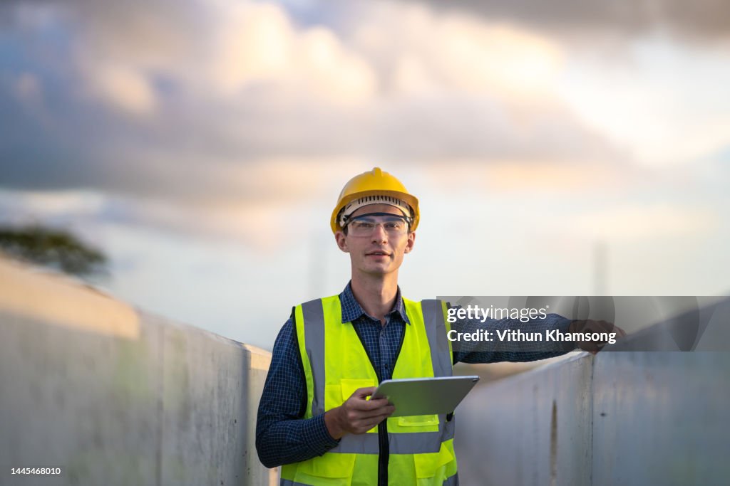 Engineer and tablet check quality concrete at heavy construction site.