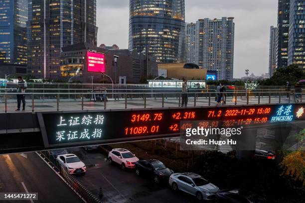 People walk on a pedestrian bridge which displays the numbers for the Shanghai Shenzhen stock indexes on November 29, 2022 in Shanghai, China.