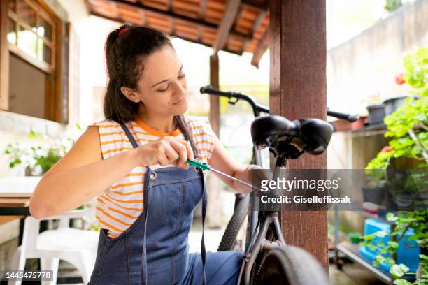 junge frau fixiert ihren fahrradsitz mit schraubenzieher - fahrradsattel stock-fotos und bilder