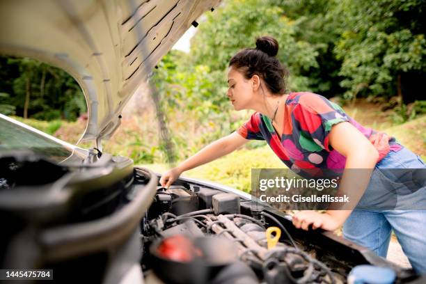 young woman checking her car battery connection - car inspection stock pictures, royalty-free photos & images