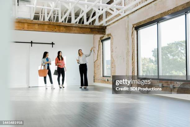 real estate agent gestures while explaining office features to customers - commercial property imagens e fotografias de stock