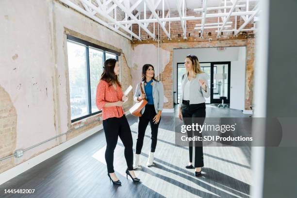 businesswoman asks female real estate agent questions while touring office space - commercieel vastgoed stockfoto's en -beelden