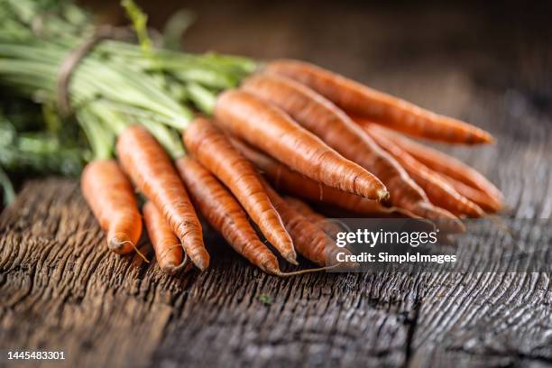 fresh carrots laid loosely on an old table. - carrot fotografías e imágenes de stock